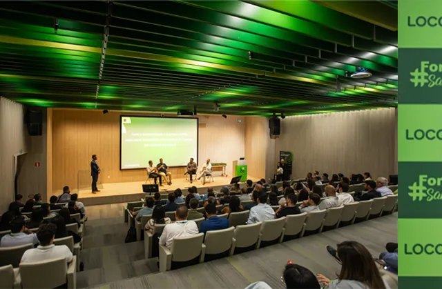 Evento Localiza — painel e plateia no auditório